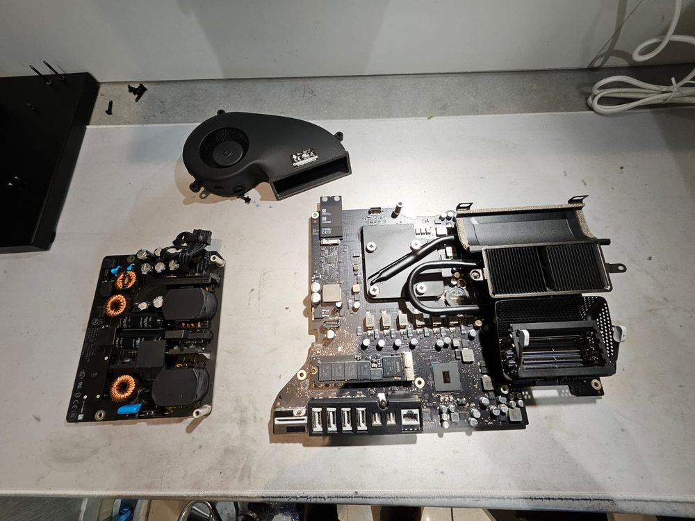 A disassembled iMac on the bench, logic board, cooling fan and heatsink separated for repair
